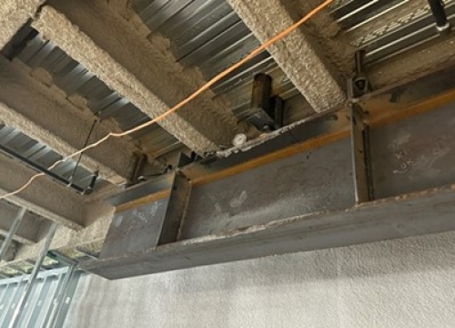 Deadman anchor beam concealed below the atrium to terminate the tension rods. 